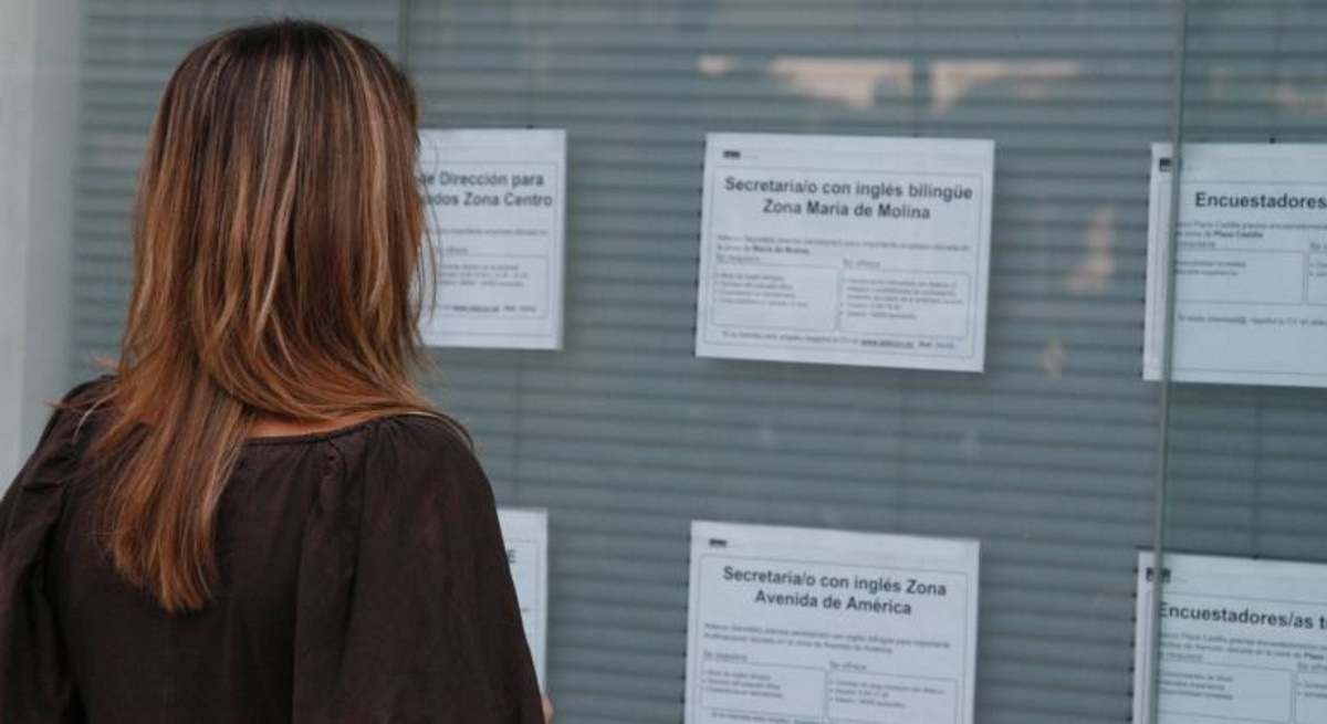 Mujer joven consulta anuncios de trabajo en una ETT.