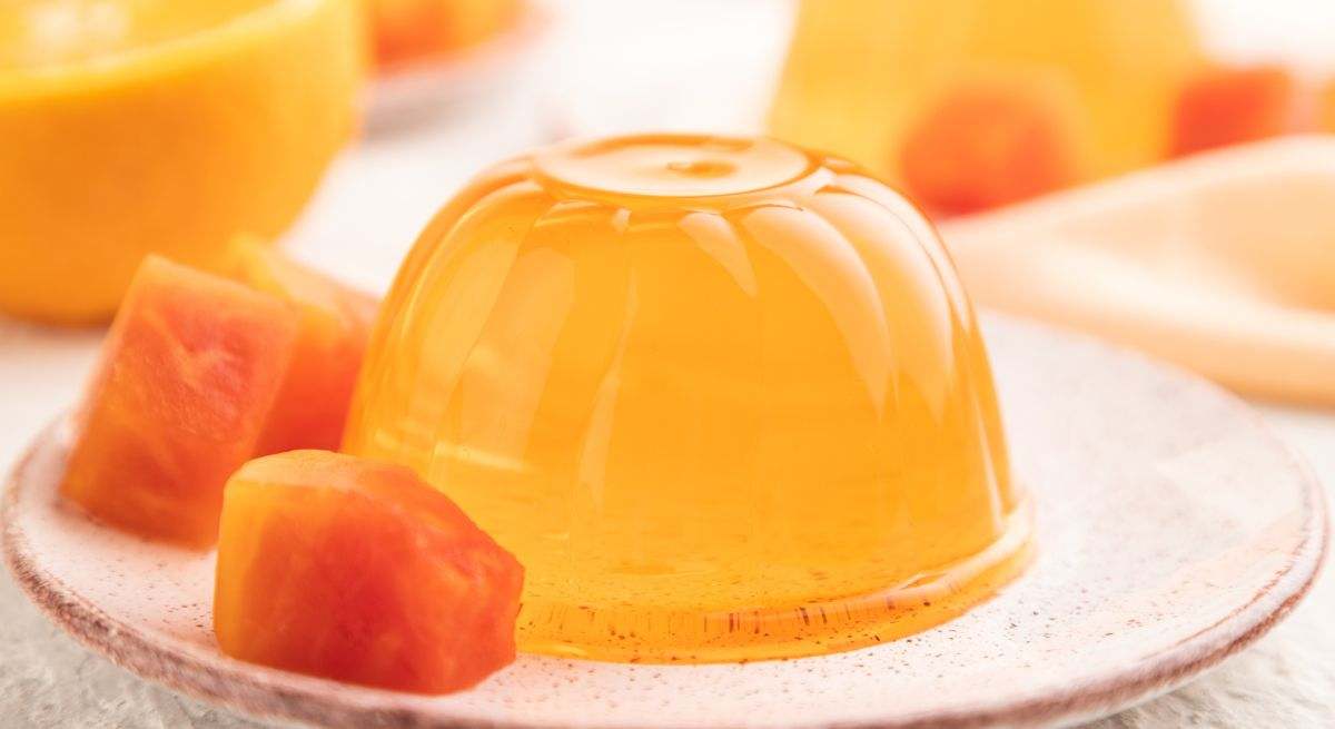 Gelatina naranja con trozos de comida al lado