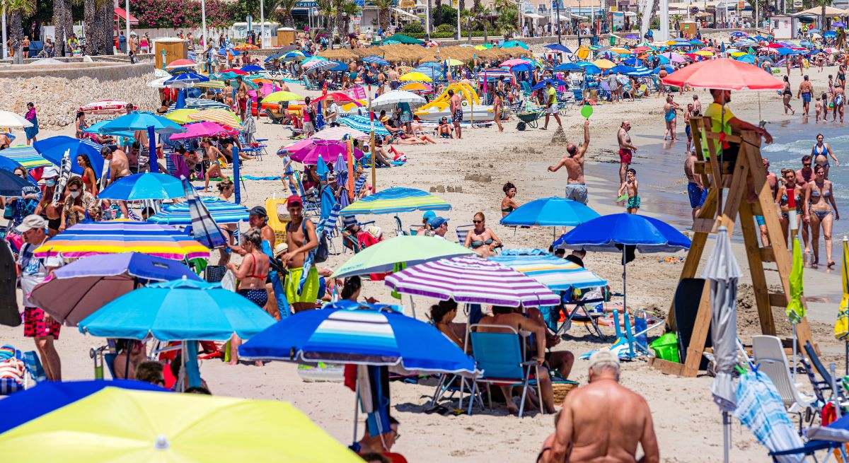 Playa con sombrillas coloridas y mucha gente.