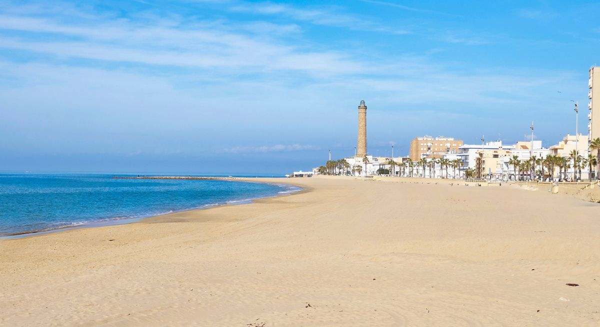 playa de arenas blancas con el faro al fondo