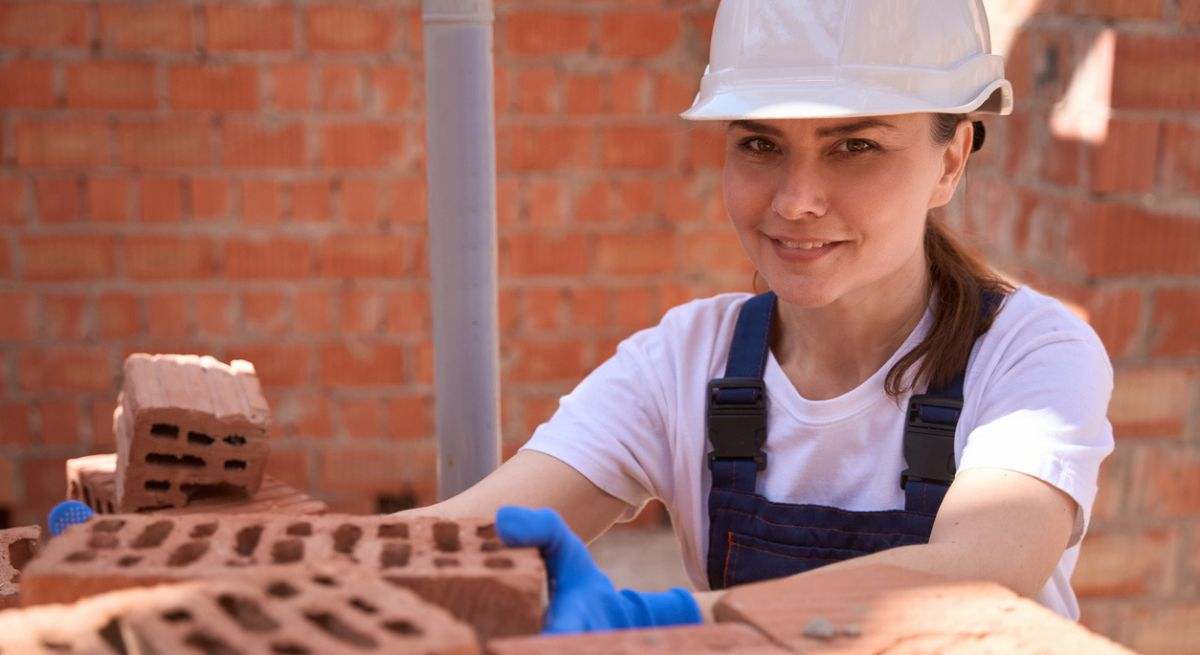 Mujer con casco blanco poniendo ladrillos