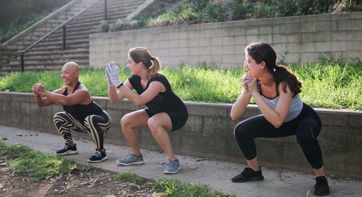 Un grupo de mujeres realiza sentadillas en un parque