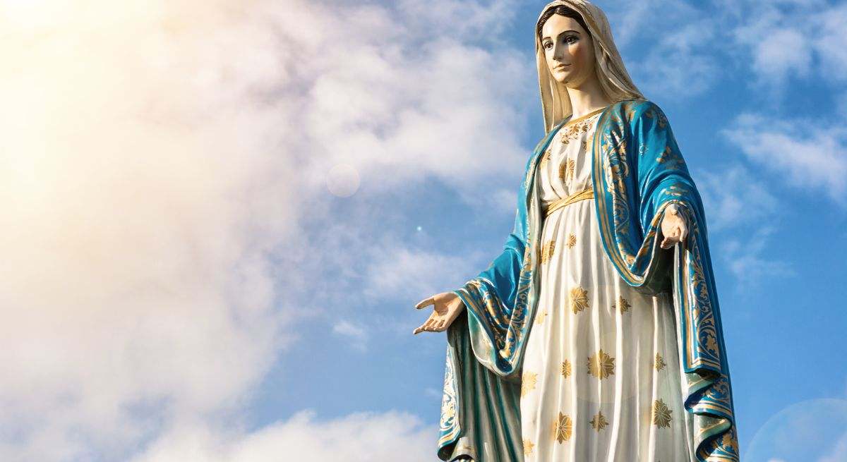 Estatua de la Virgen María con el cielo y las nubes de fondo