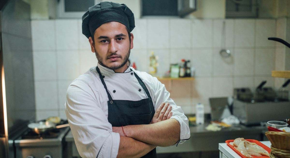 Un chef con gorro de cocinero en la cocina de su local