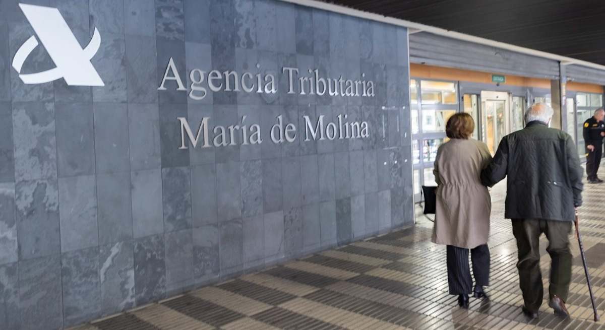 Dos personas mayores pasan por delante de una oficina de la Agencia Tributaria.