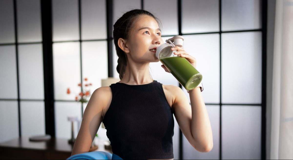 Joven deportista tomando un batido de color verde