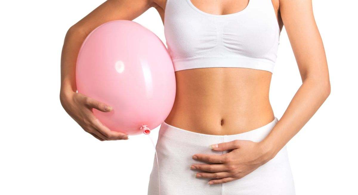 Una mujer se toca la tripa mientras sujeta un globo