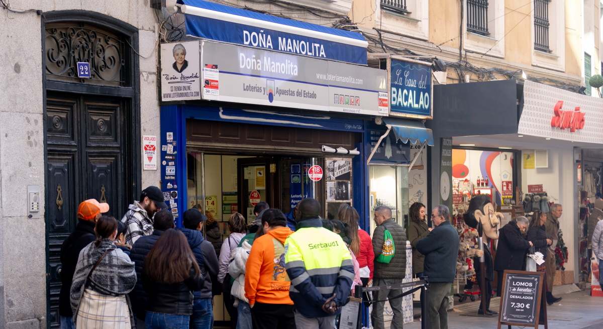 Varias personas hacen cola para comprar Lotería de Navidad en Doña Manolita.