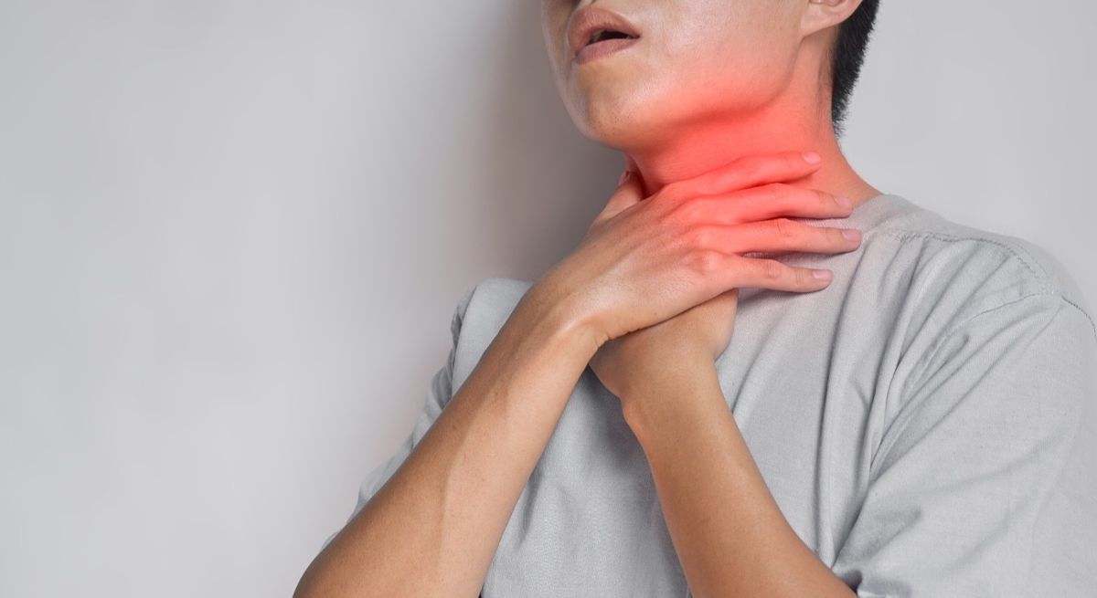 Hombre con las manos en el cuello por esofagitis