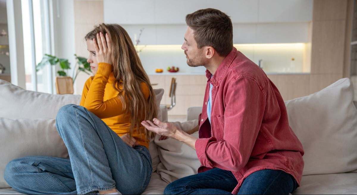 Pareja discutiendo sentada en el sofá