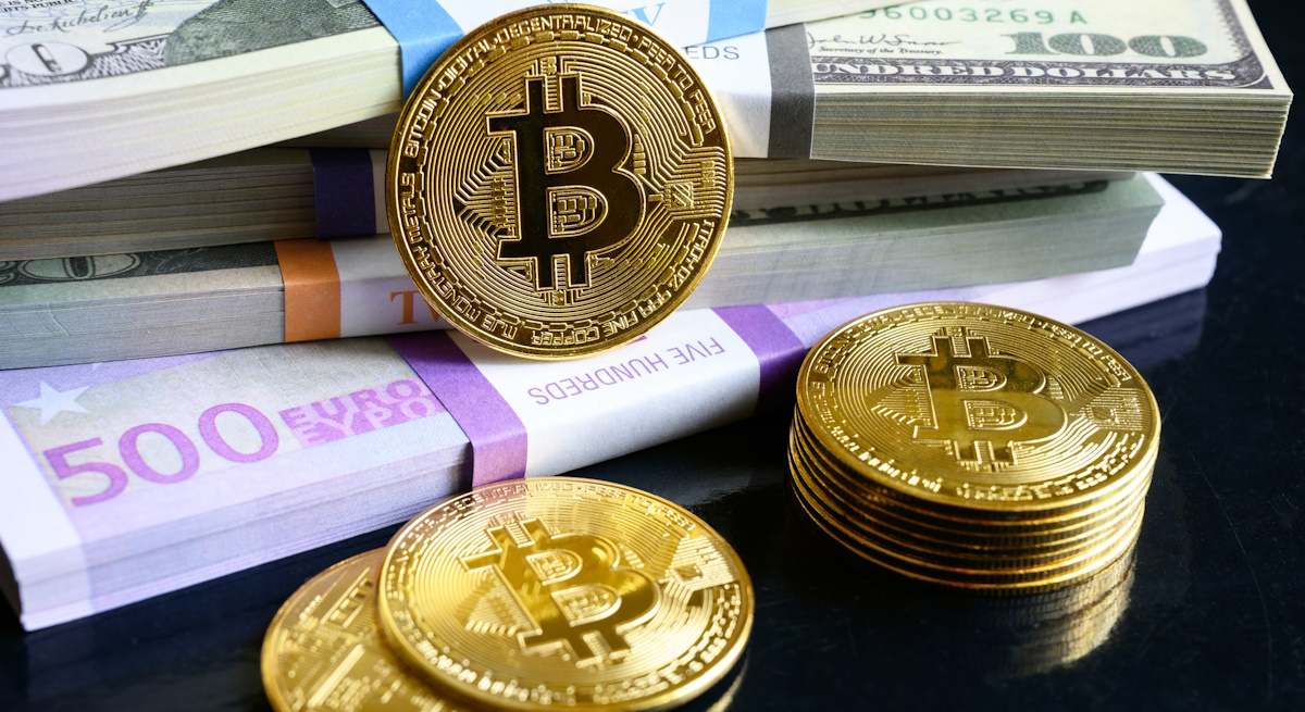 Bitcoins junto a billetes de euros y dólares