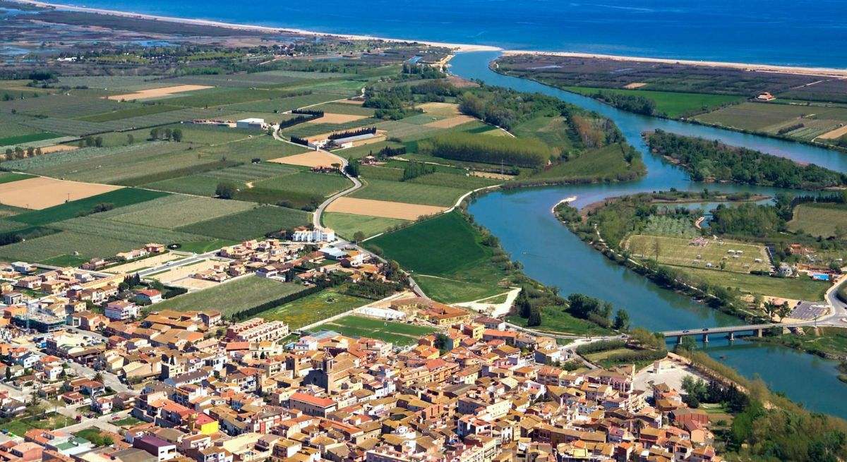 Vista aérea en la que se puede apreciar el mar y el río junto al pueblo de casas rojas