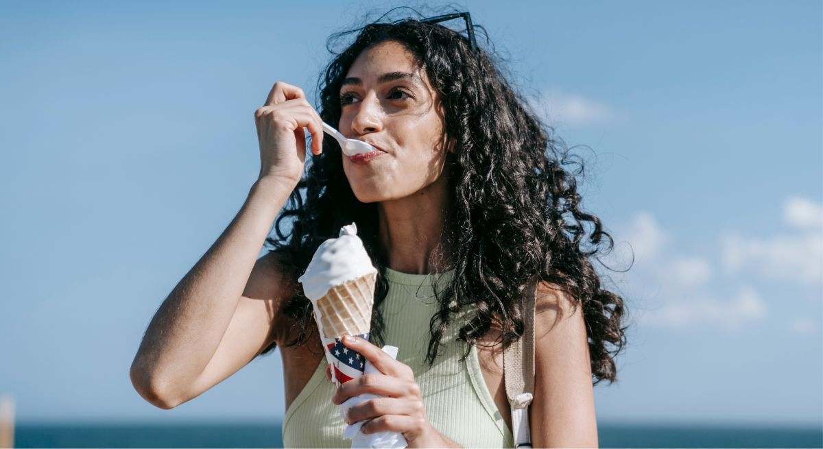 Una mujer come un helado en la playa