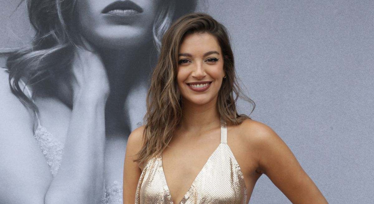 Ana Guerra posando en un photocall con un top dorado