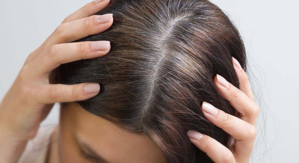 Una mujer señala sus canas