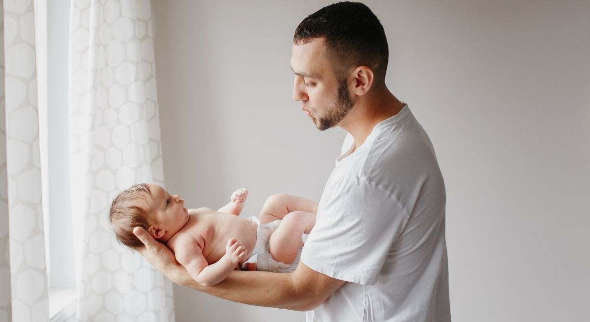 Papá tiene a su bebé en brazos y le hace gestos con la cara para que no llore