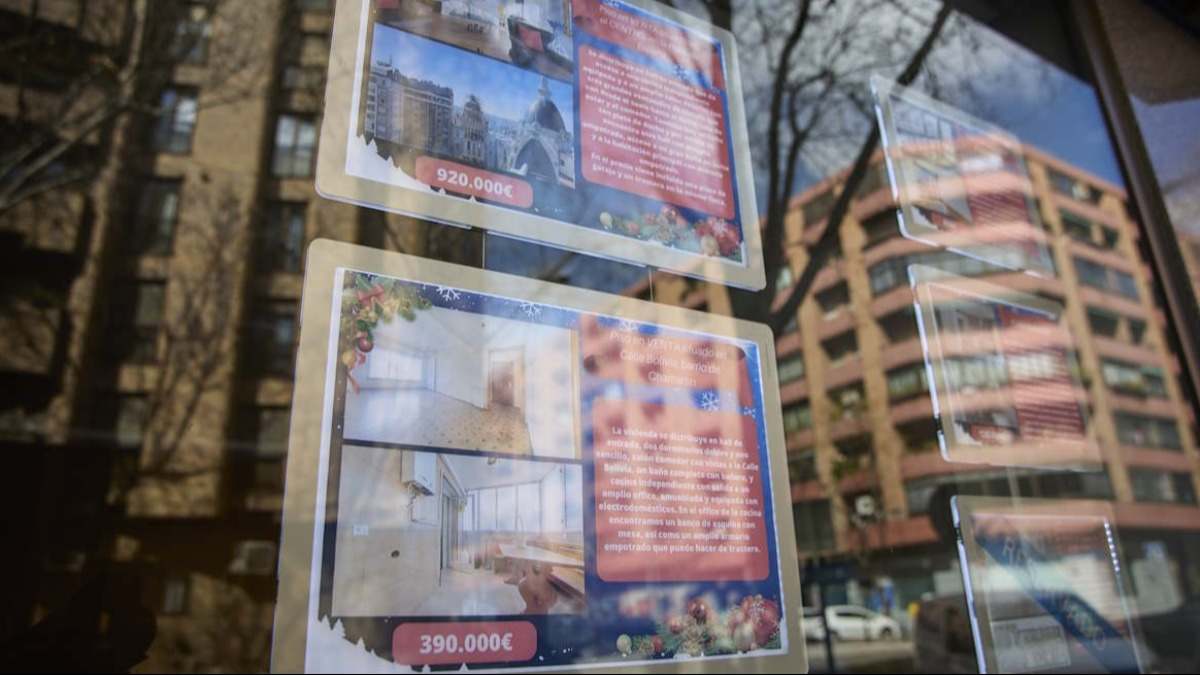 Anuncios de pisos en venta en el escaparate de una agencia inmobiliaria.