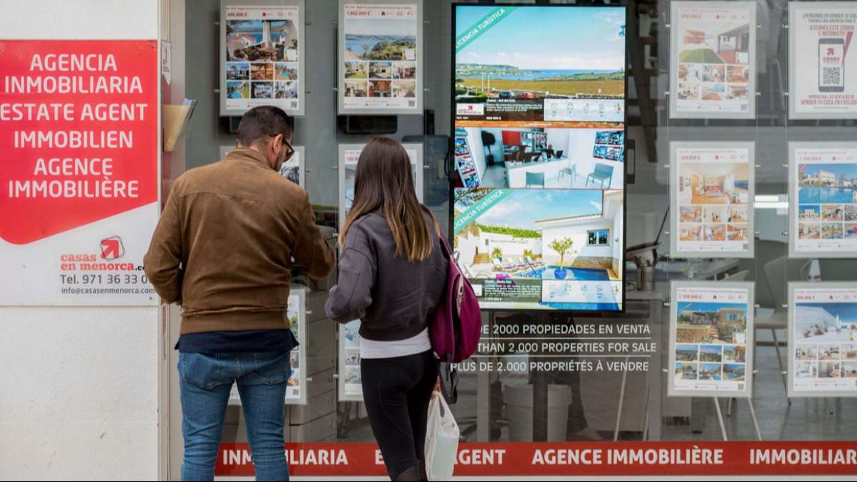 Una pareja mirando un escaparate de una inmobiliaria con pisos en alquiler