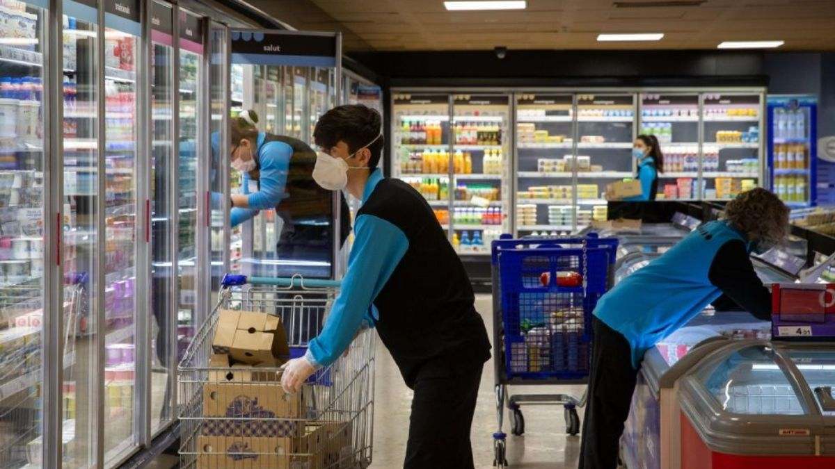 Varios trabajadores reponen alimentos en un supermercado español