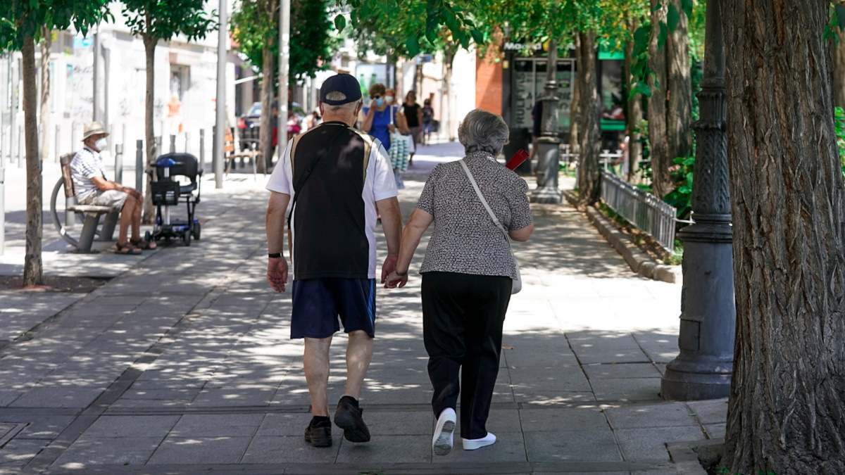 Una pareja de jubilados pasea por la calle.