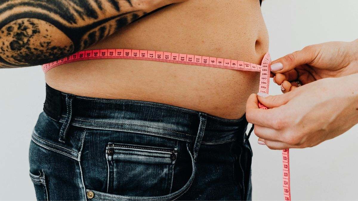 Una hombre se mide la cintura mientras sigue una dieta estricta para perder peso