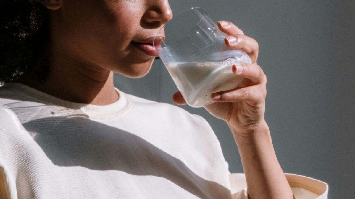 Una mujer bebe un vaso de leche, que aporta muchos nutrientes
