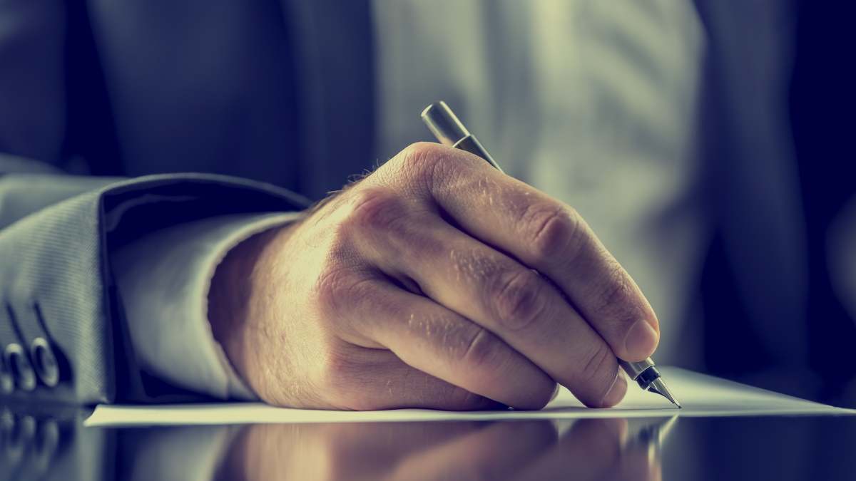 Fotografía detalle de una persona firmando un documento.