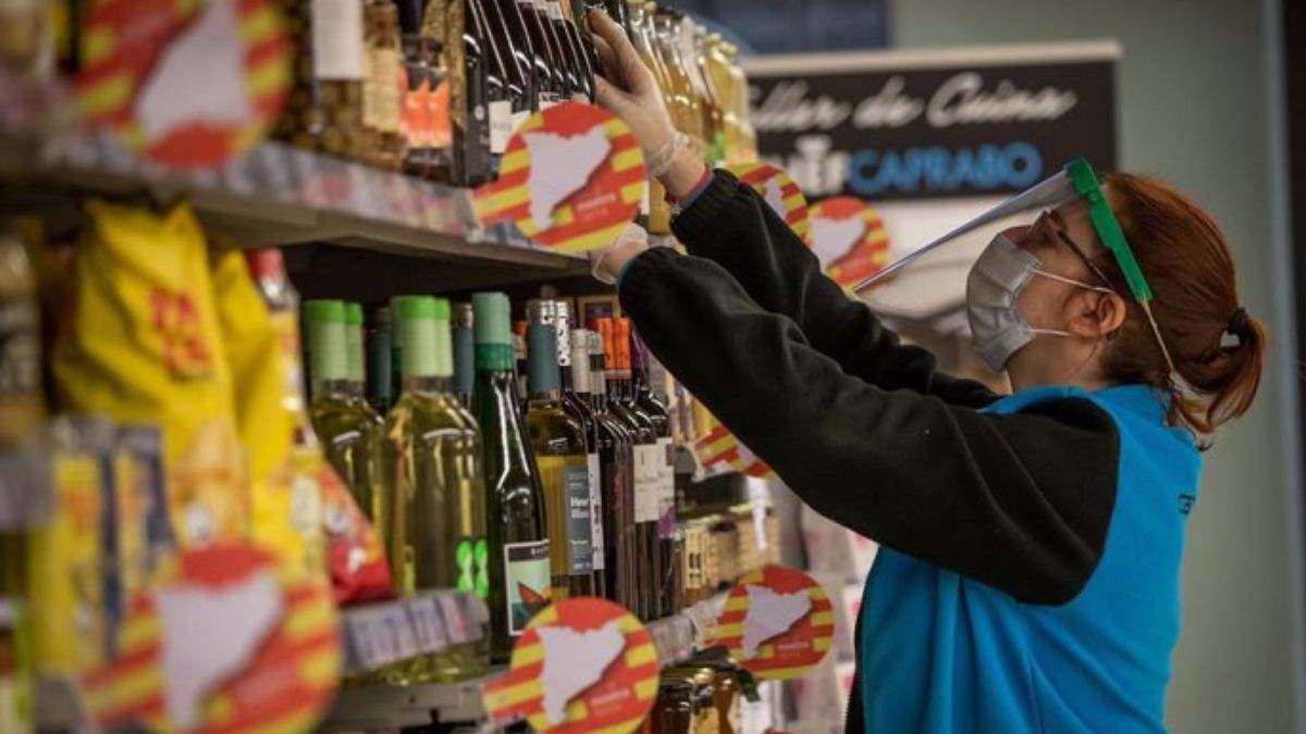 Una trabajadora repone productos en un supermercado español