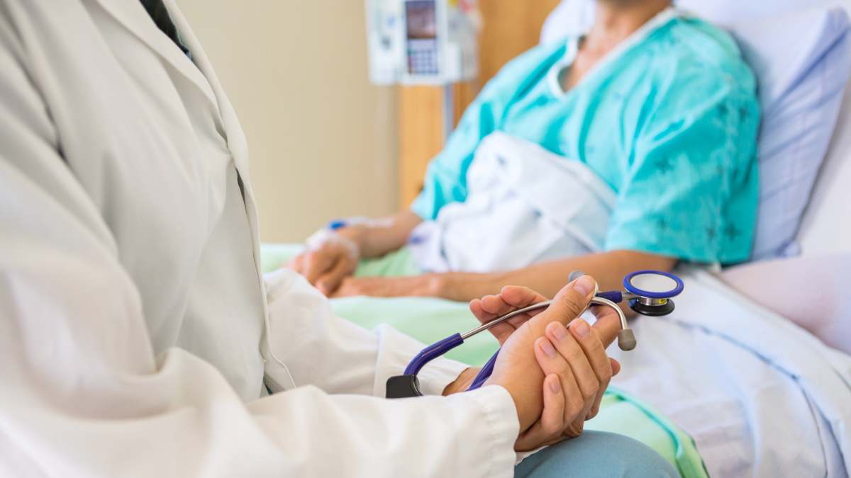 Imagen de recurso de un doctor atendiendo a un paciente en la cama de un hospital.