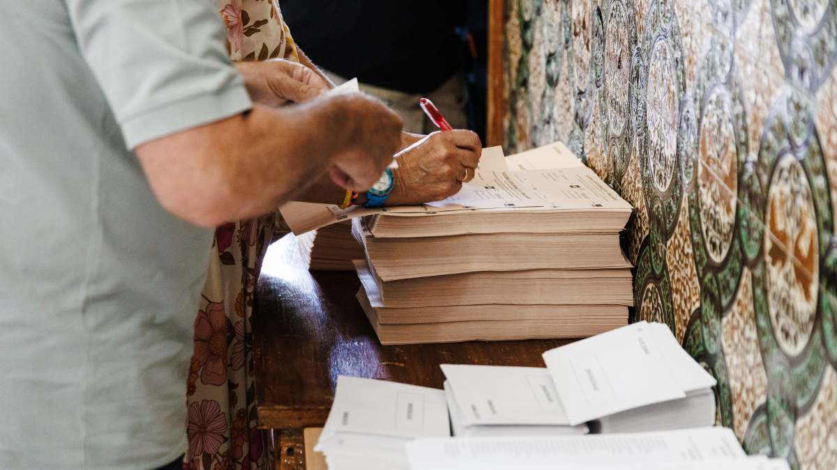 Varias personas rellenan papeletas para las elecciones del 23J.