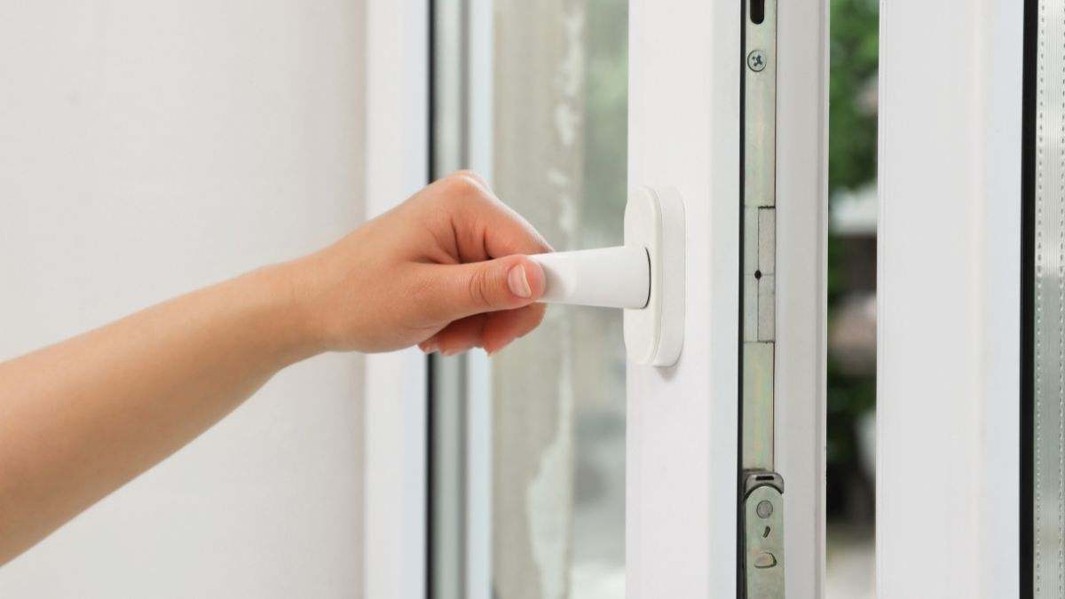 Una persona abre una ventana para ventilar.