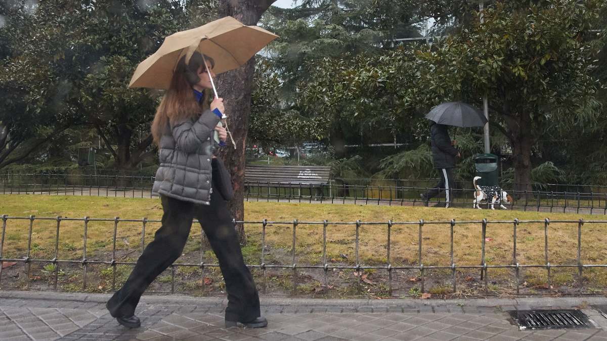 Una mujer se protege de la lluvia con un paraguas.