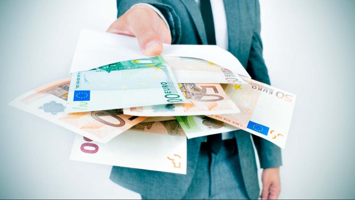 Un hombre ofrece múltiples billetes en su mano
