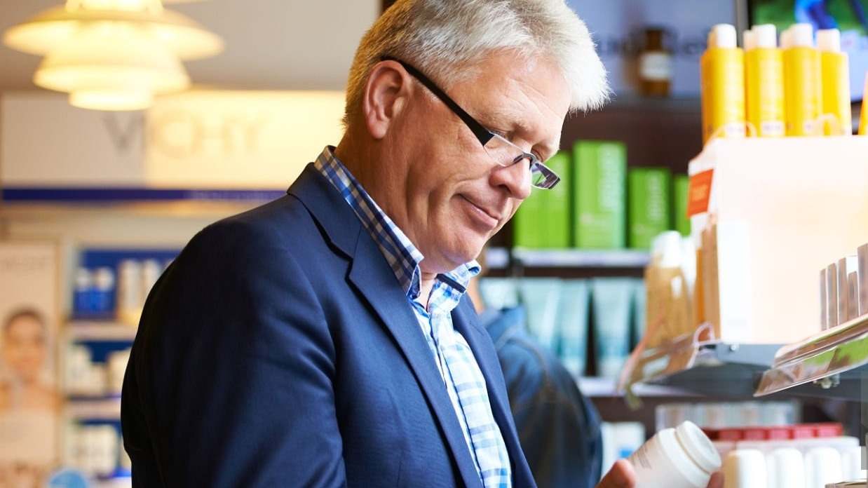 Hombre de mediana edad mirando un bote de vitaminas