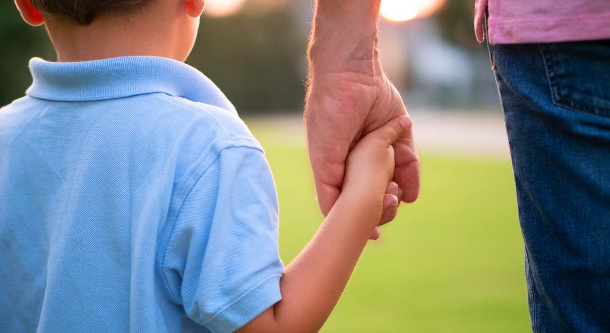 un adulto coge de la mano a un menor