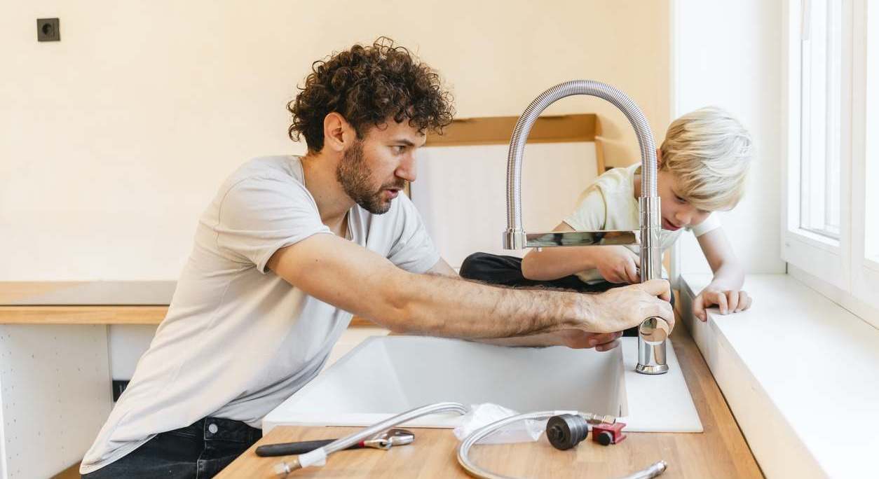 Padre arreglando junto a su hijo el fregadero