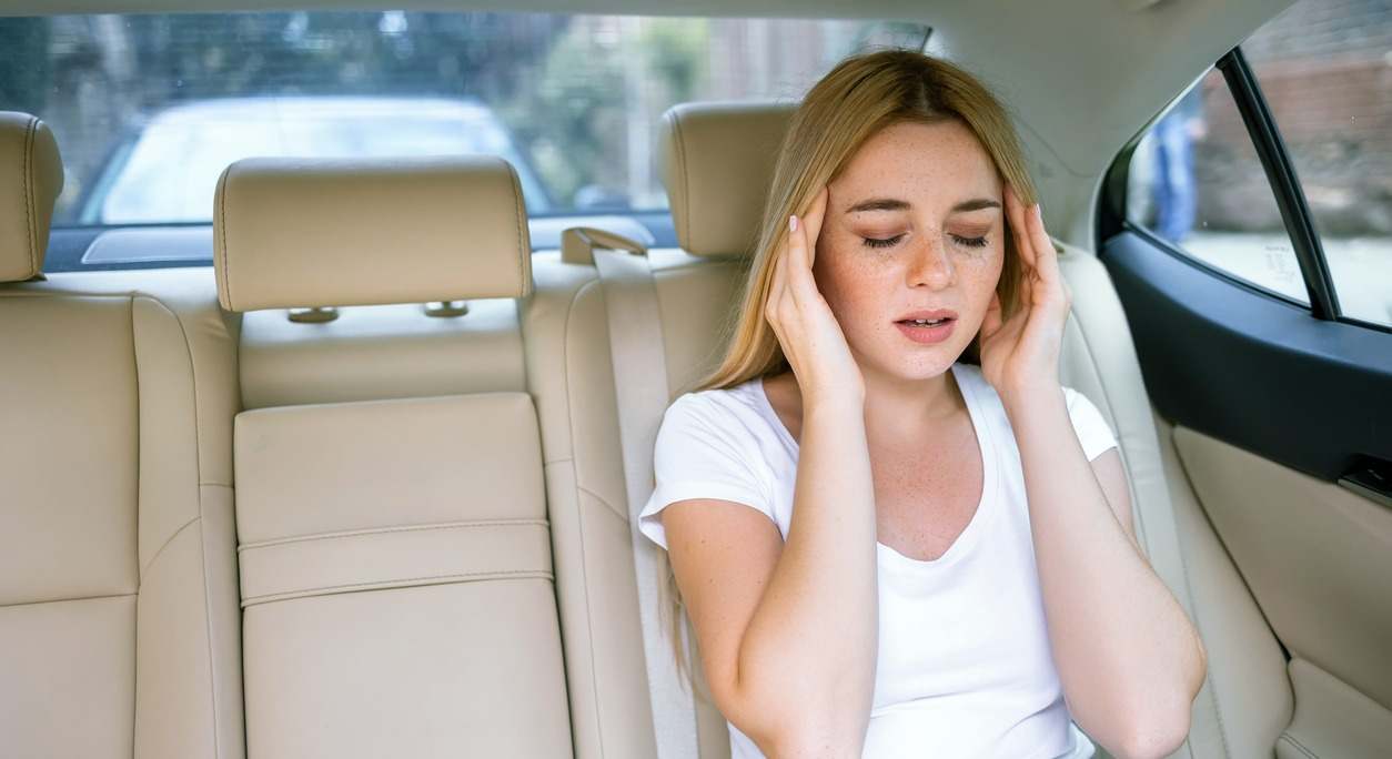 una mujer mareada en el asiento de atrás de un coche