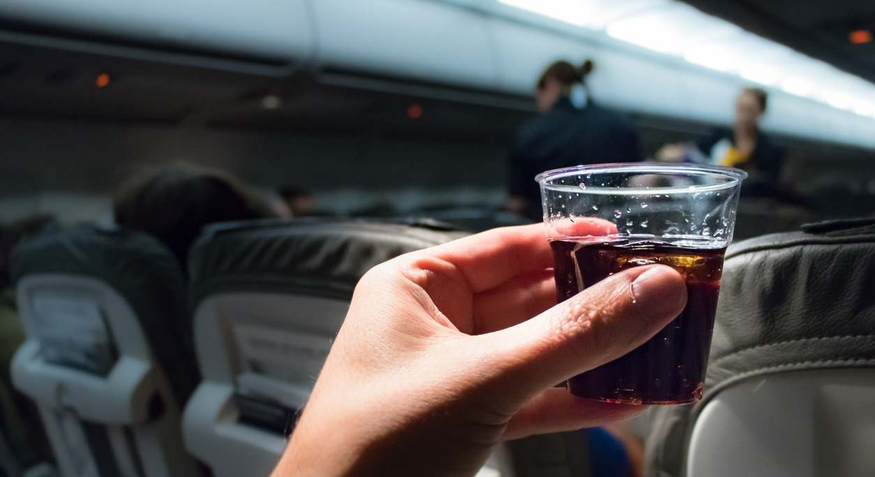 Un pasajero toma una bebida dentro de un avión