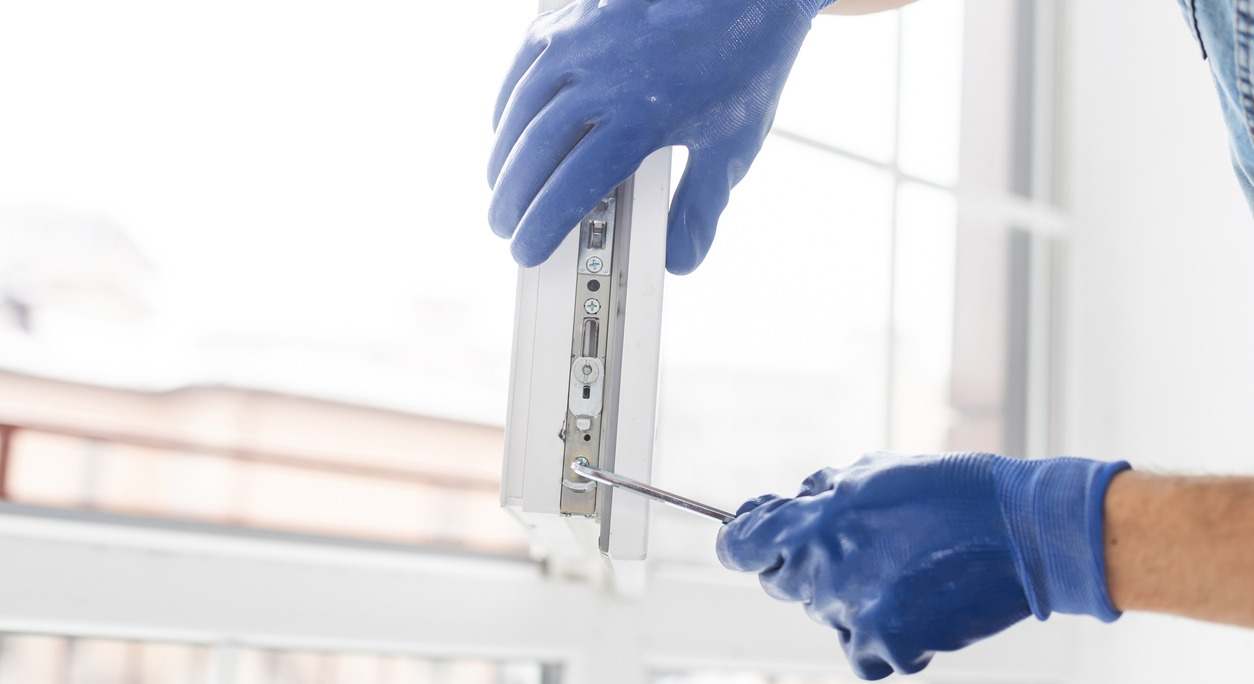 Un trabajador con guantes revisa la cerradura de una ventana