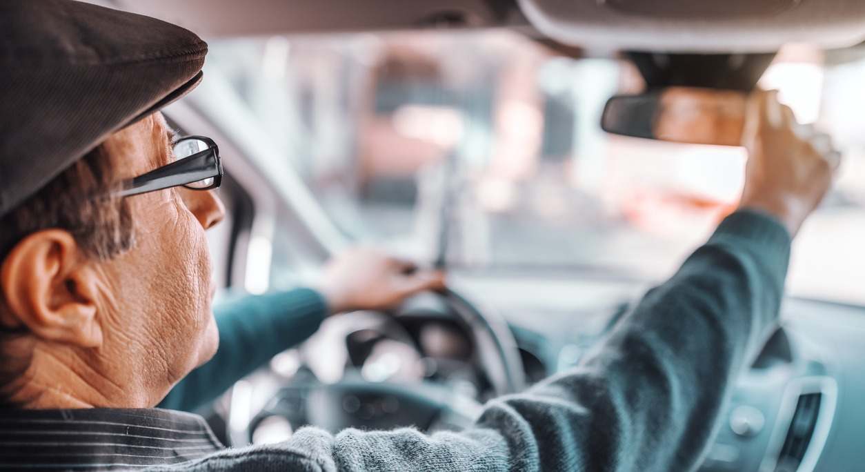 un conductor ajusta el espejo retrovisor