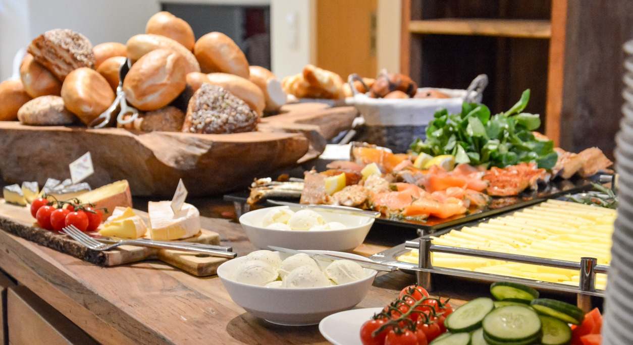 Un desayuno buffet con panecillos, queso y varias verduras