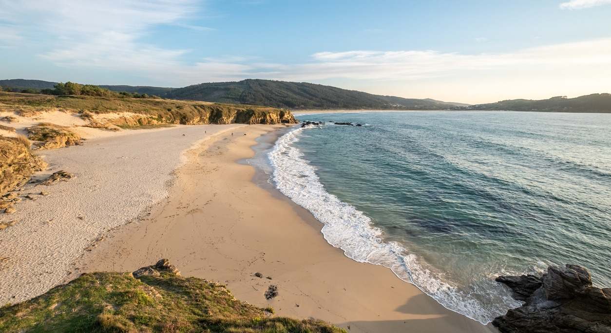 La playa de Esmelle en Ferrol se extiende con un largo arenal que choca con sus aguas cristalinas