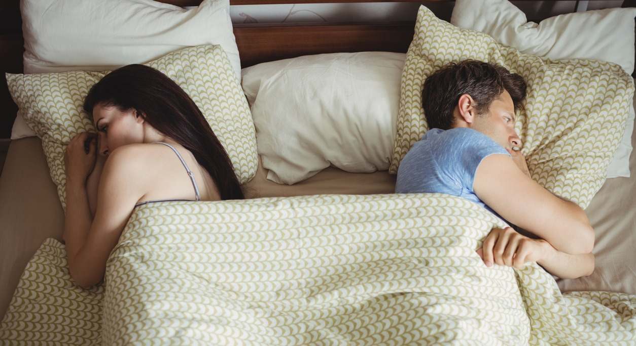 una pareja duerme separada en la cama