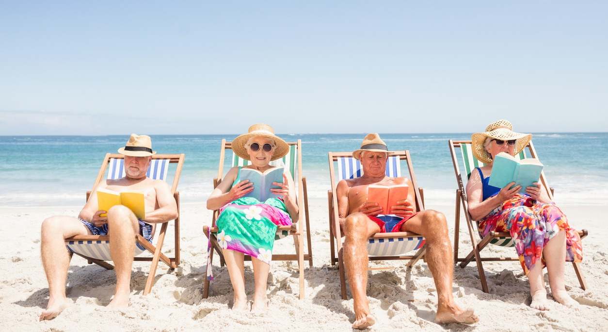 Señores mayores leyendo en la playa