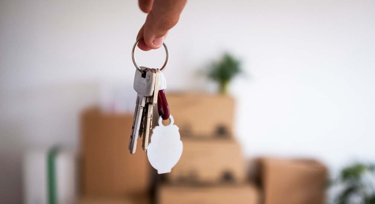 Primer plano de las llaves del nuevo apartamento vacío con cajas móviles en el suelo