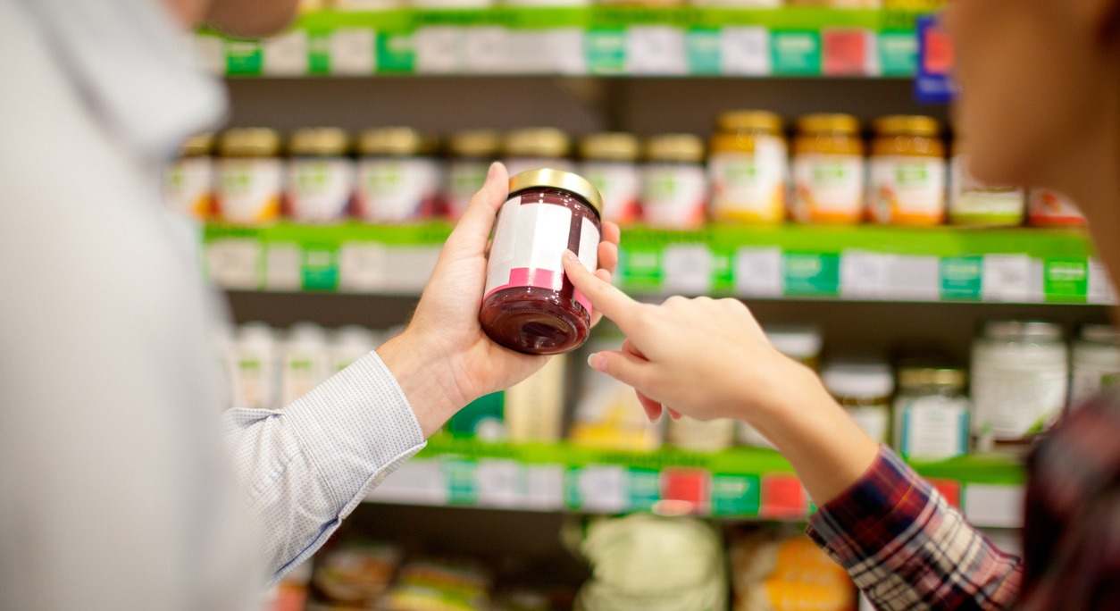 dos clientes observan el etiquetado de un envase de mermelada