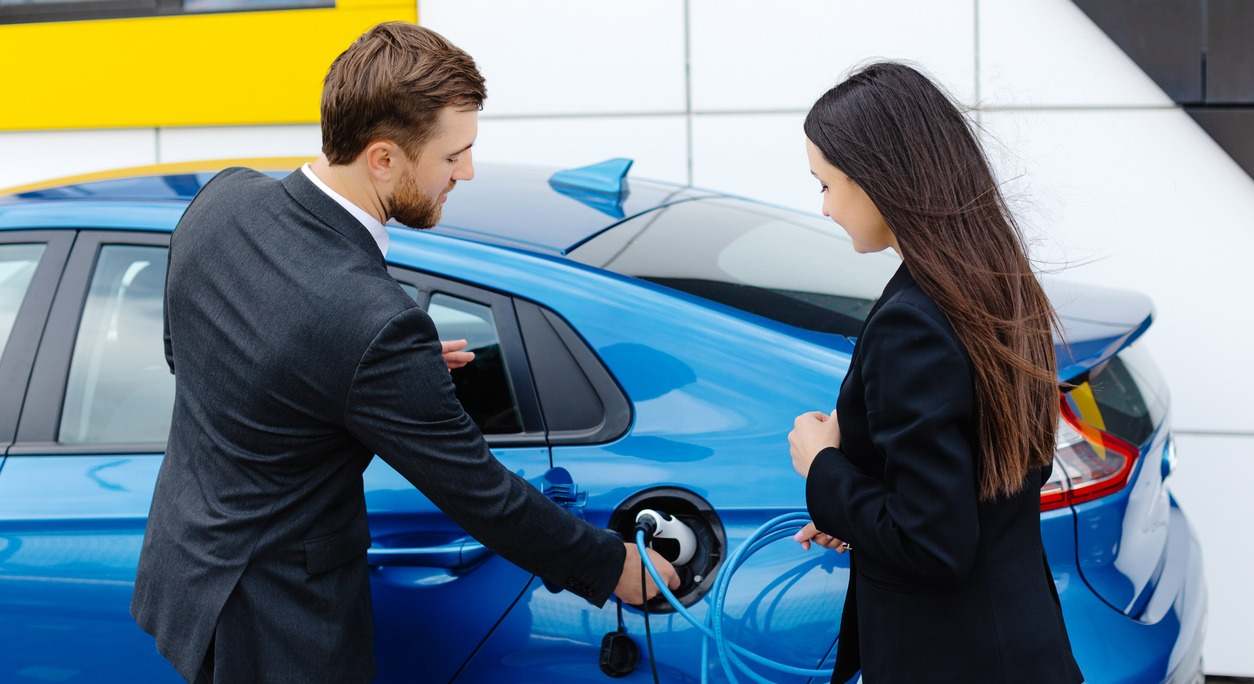 un vendedor muestra un coche eléctrico a una compradora