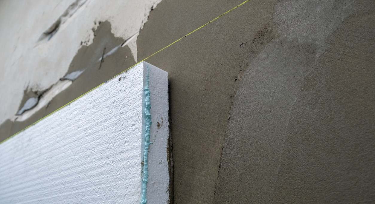 Instalación de láminas de espuma de poliestireno en la pared de la casa para aislarla térmicamente