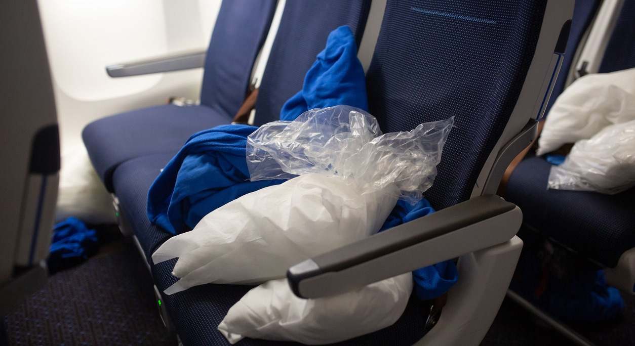 Asiento de un avión con las mantas de fibras acrílicas fuera de sus bolsas de plástico.
