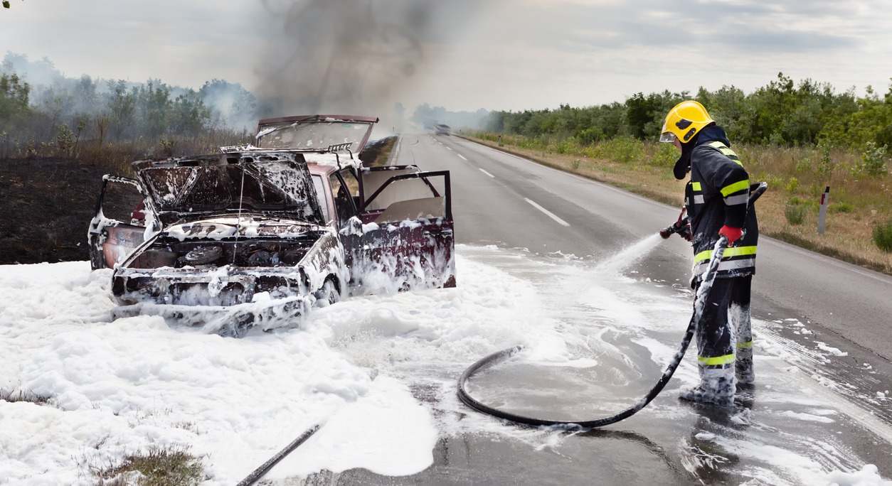 Un bombero apaga un coche en llamas